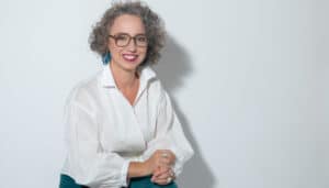 Christine Maria Kaltenleitner sitzt im Sommer in weisser Bluse auf einem Stuhl. Referentin des MC Lago Webinars «Der unterschätzte Erfolgsfaktor: Selbstwertgefühl» am 24. August 2026.