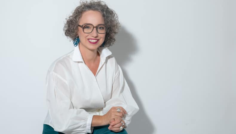 Christine Maria Kaltenleitner sitzt im Sommer in weisser Bluse auf einem Stuhl. Referentin des MC Lago Webinars «Der unterschätzte Erfolgsfaktor: Selbstwertgefühl» am 24. August 2026.