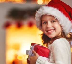 Lachendes Kind hält ein bunt verpacktes Weihnachtsgeschenk