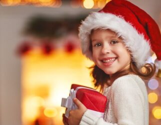 Lachendes Kind hält ein bunt verpacktes Weihnachtsgeschenk