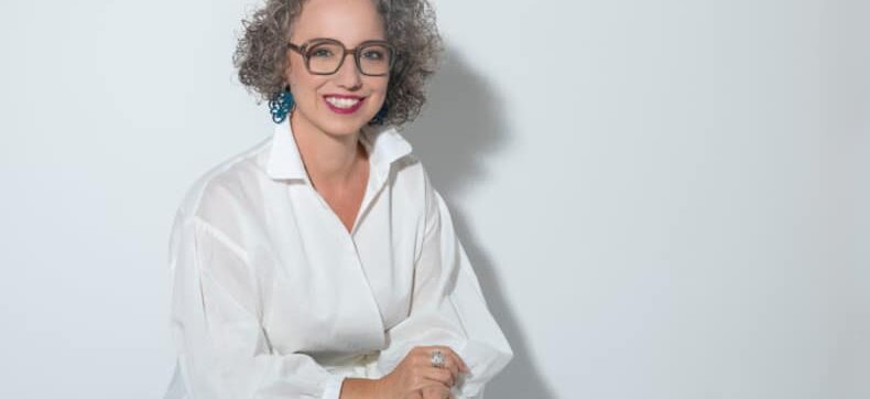 Christine Maria Kaltenleitner sitzt im Sommer in weisser Bluse auf einem Stuhl. Referentin des MC Lago Webinars «Der unterschätzte Erfolgsfaktor: Selbstwertgefühl» am 24. August 2026.